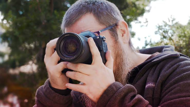 25 Essential Photography Tips For Beginners In 2026 2 Beginner photographer adjusting aperture, shutter speed, and ISO settings on a digital camera